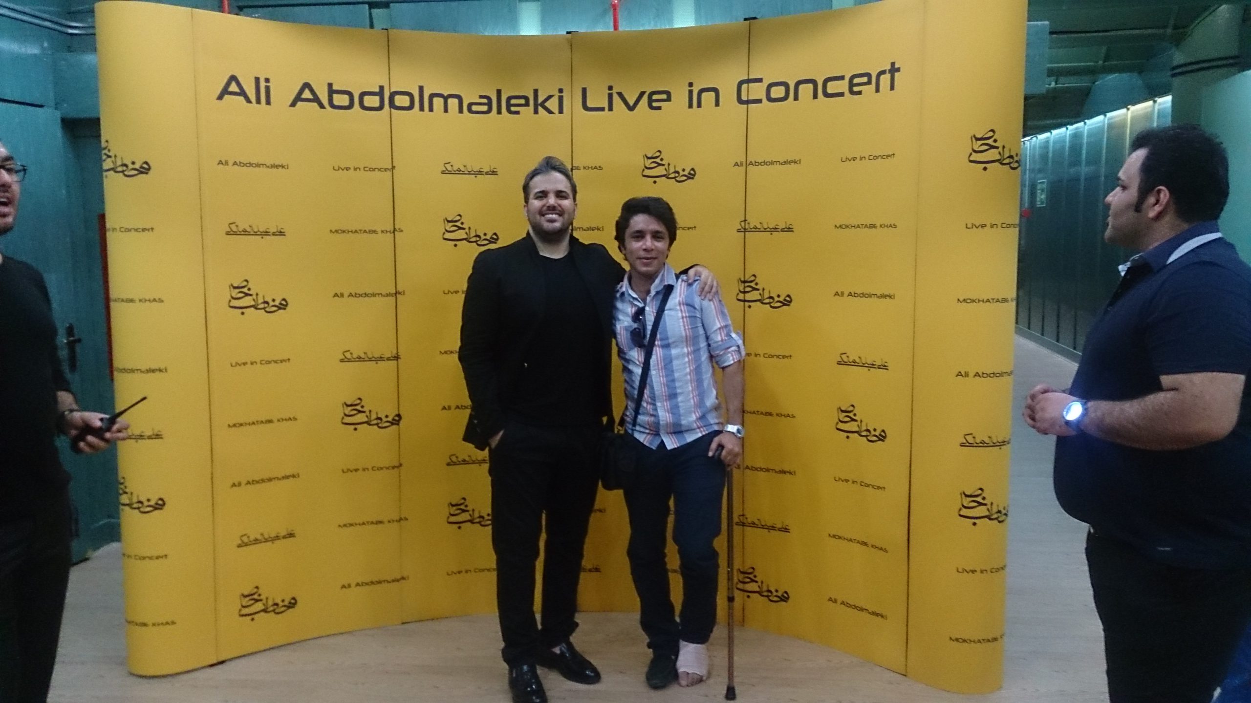arash bahmani with a broken leg directing an Ali abdolmaleki concert